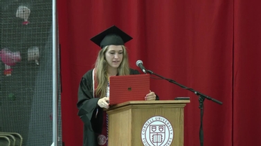 A graduate speaking at a podium.